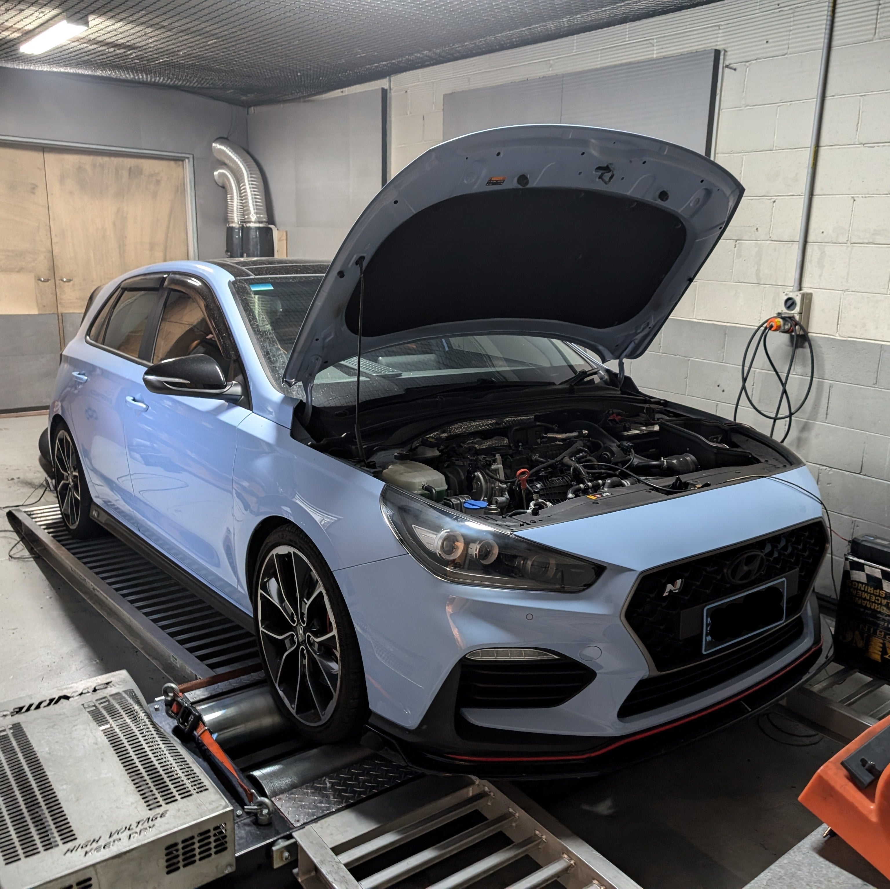 Blue car on a lift with open hood in a garage. Tuning. 